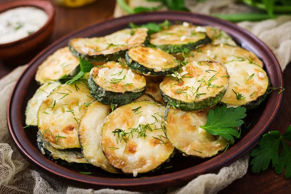 Ropogós, aranybarna cukkini szeletek friss fűszerekkel tálalva.