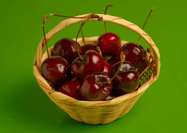 Kosárban friss, lédús meggyek zöld háttér előtt, ideális fagyasztásra.